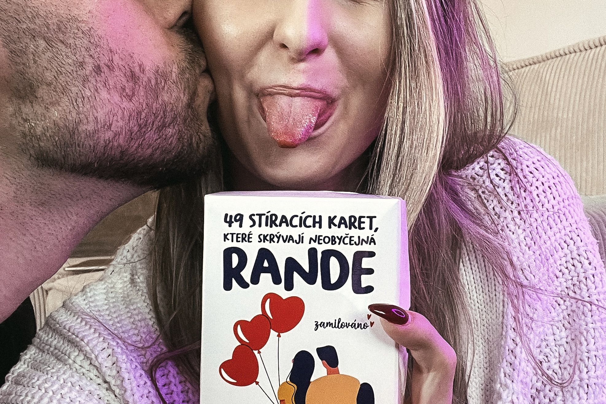 Pár, co si dává pusu na tvář a v ruce drží párové, stírací karty